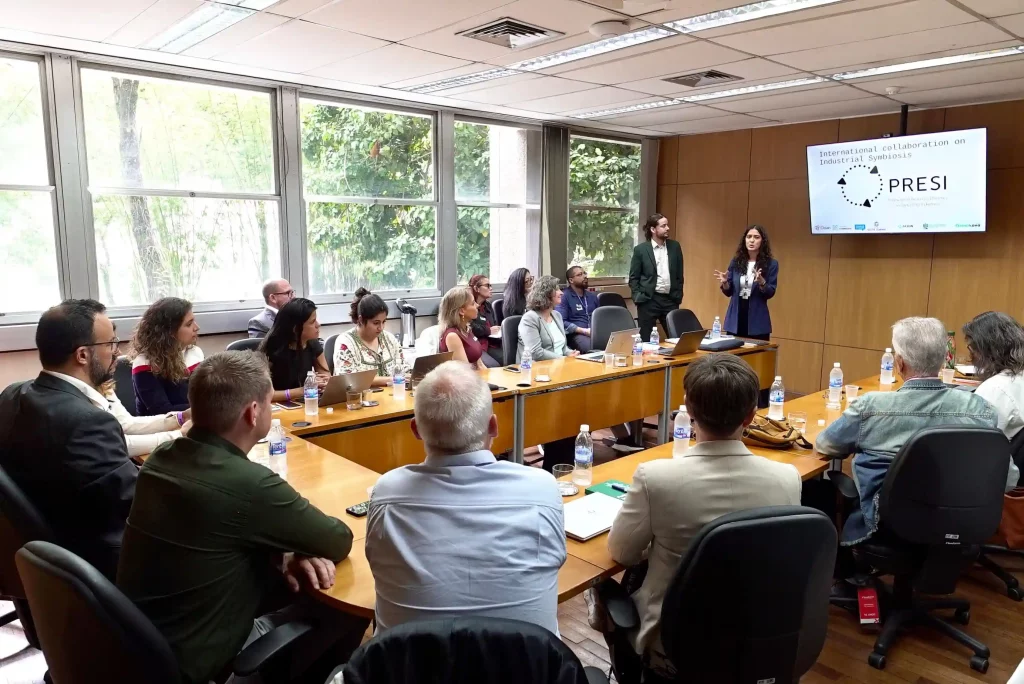 Pessoas estão sentadas ao redor de uma mesa de reunião para discutir o Guia de Facilitação da Simbiose Industrial